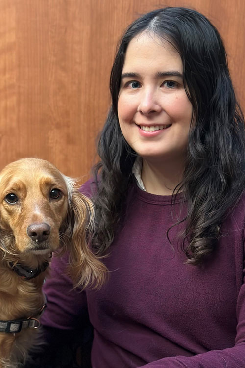 Upper bodyshot of Dr. Devon Ueda with a dog sitting next to her.
