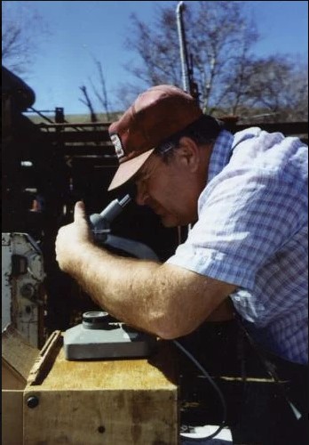 A younger Dr. Robert Cope looks at bull sperm under a microscope.