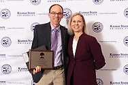 Dr. Ken Harkin holding a plaque with Dr. Beth Davis staind in front of a vet med step and repeat