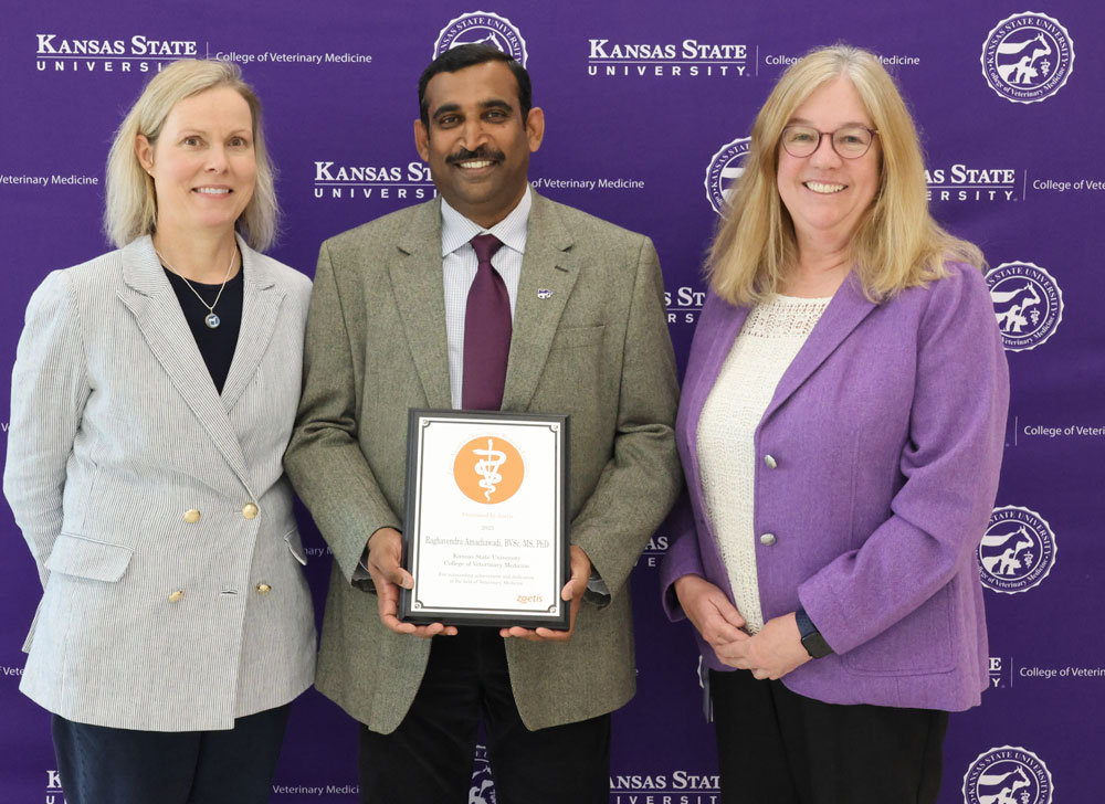 Dr. Amachawadi hods a plaque and is flanked by Dr. Davis and Dr. Dana Vanlandingham