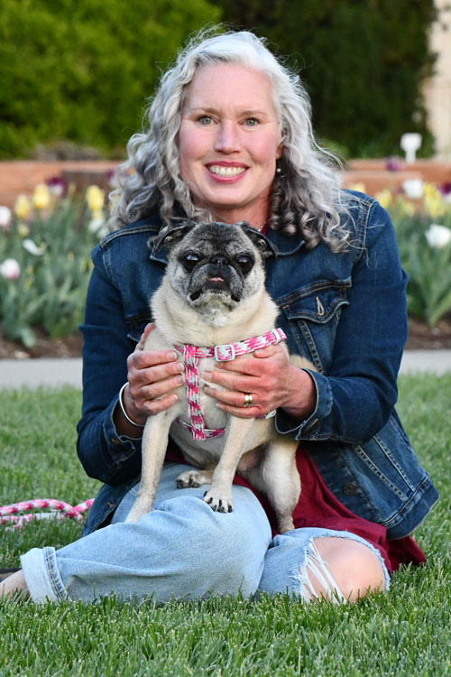 Dr. Amy Rankin sitting on the grass with her pug Pearl on her lap