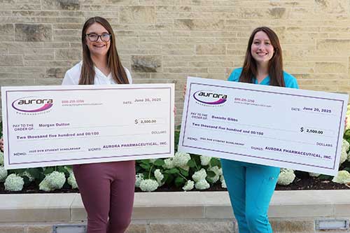 Morgan Dutton and Danielle Gibbs hold large checks