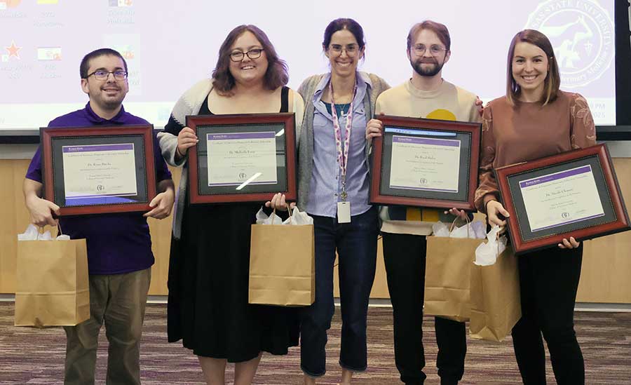 Four interns hold plaques