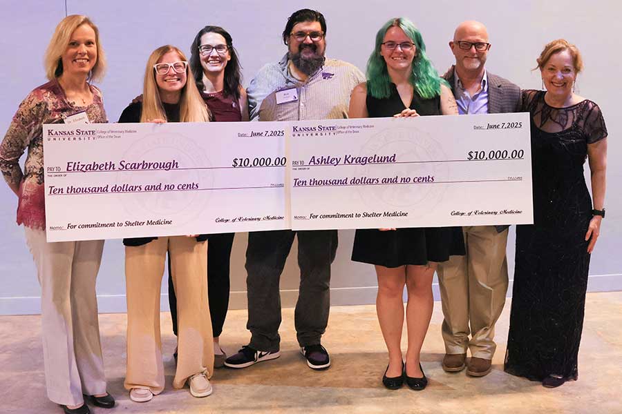Scholarship recipients hold up two big checks