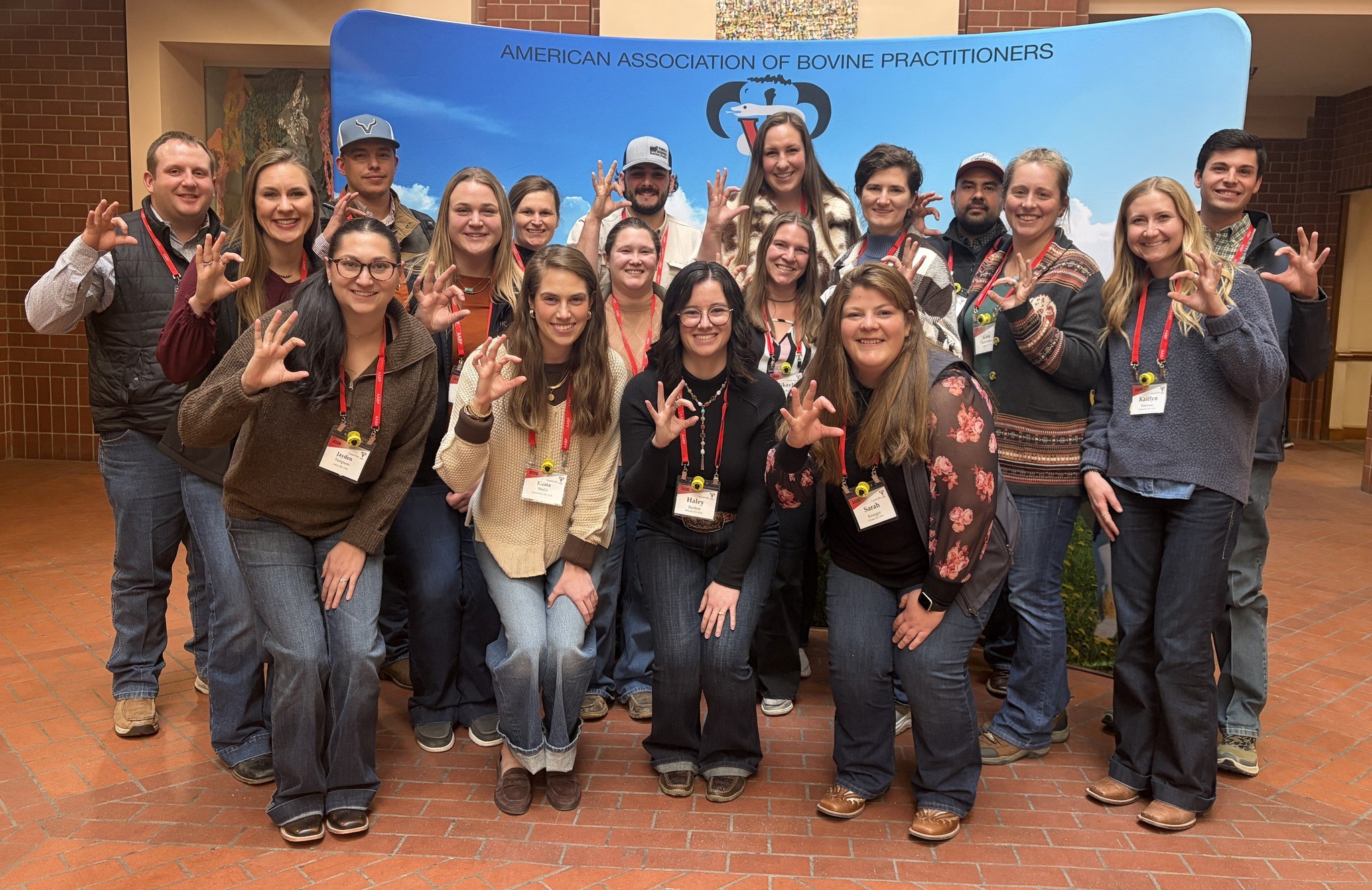 A large group of recent veterinary alumni gather in front of the AABP banner
