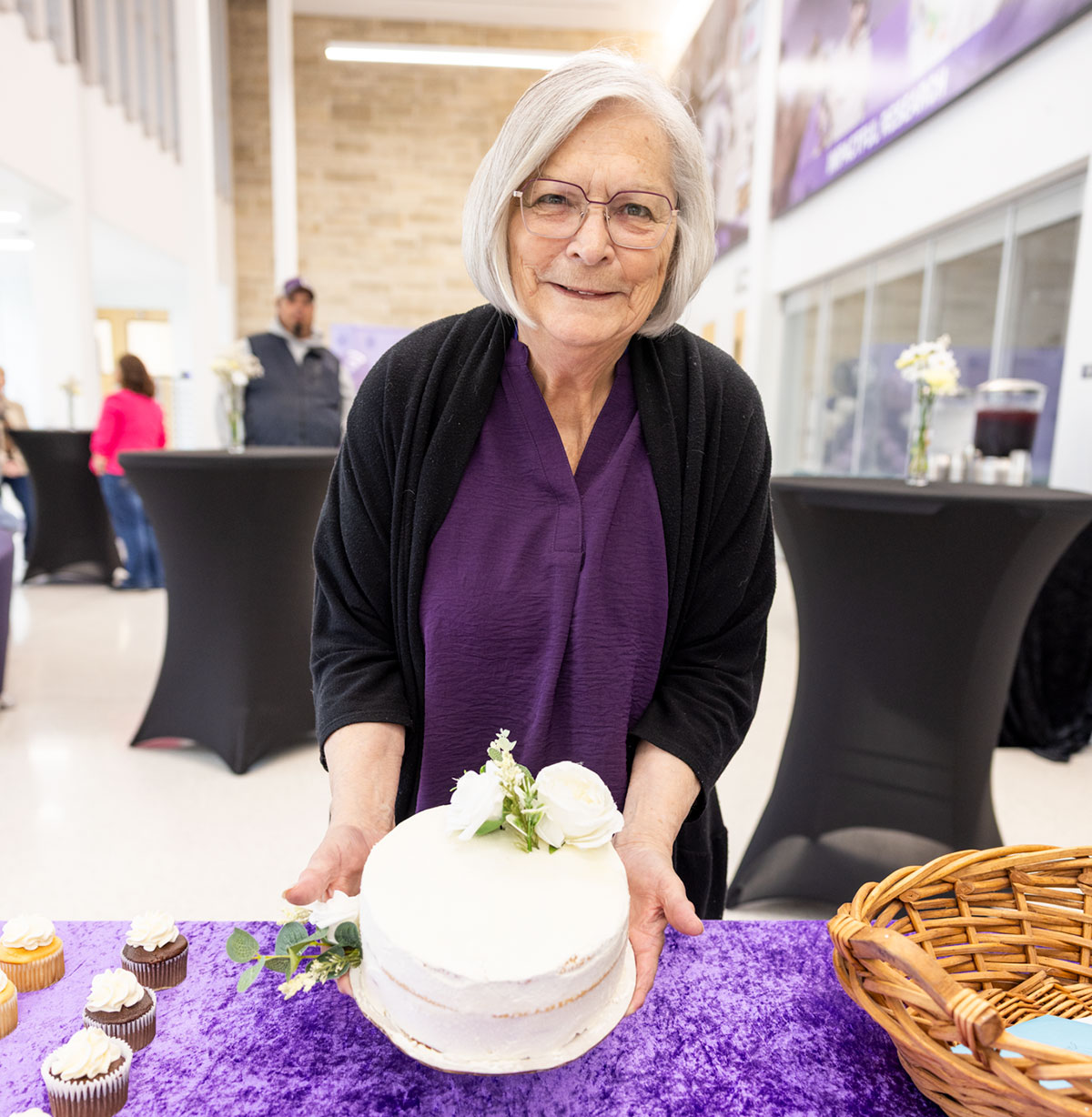 Susie Larson holds up a celebratory cake for her retirement