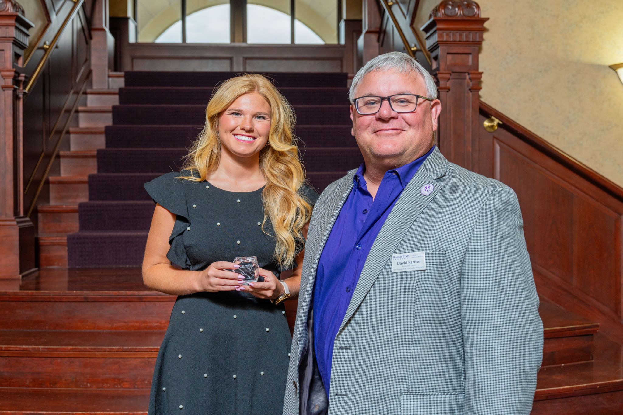 Taylor McAtee holds her crystal graduate student award while standing with Dr. David Renter