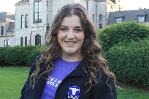Caroline Wingerts stands on lawn in front of K-State's Anderson Hall
