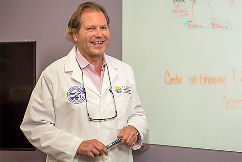 Dr. Juergen Richt stands next to a white board, wearing a white lab coat