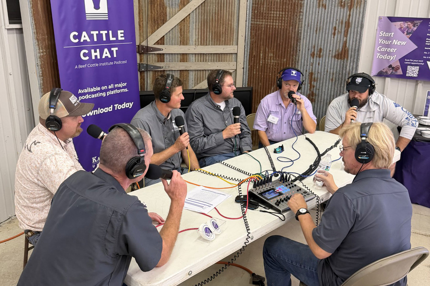 Beef veterinarians sit around a table with headphones on and holding microphones