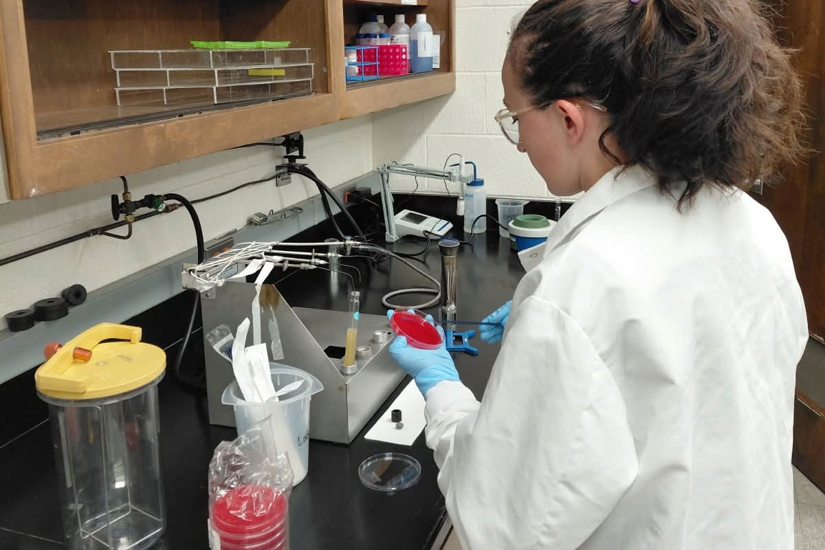 A female student holds a petri dish inside of a laboratory