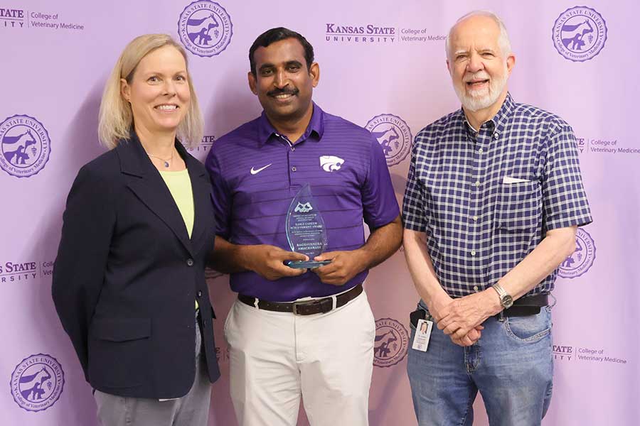 Three professors stand in front of a backdrop