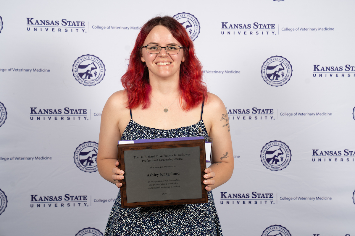 One person stands in front of a backdrop smiling.