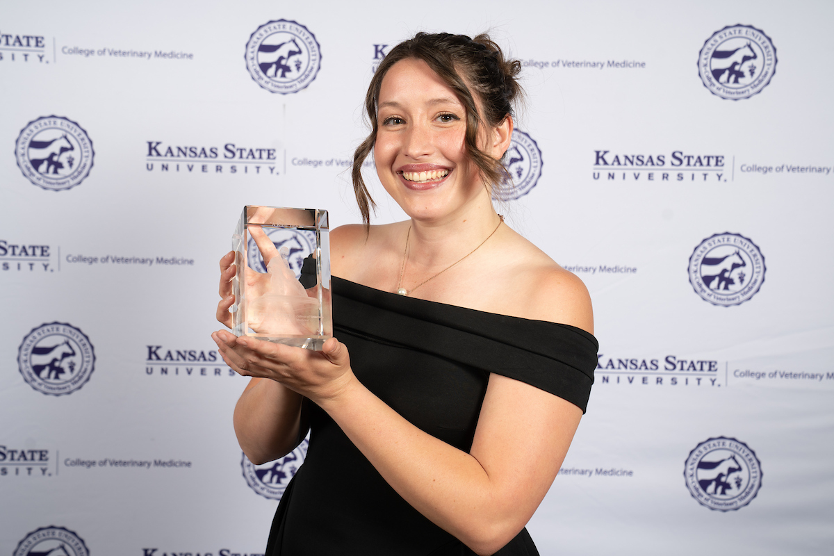 One person stands in front of a backdrop smiling.