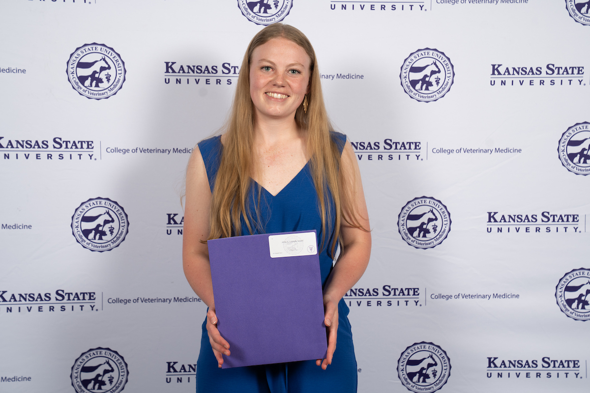 One person stands in front of a backdrop smiling.