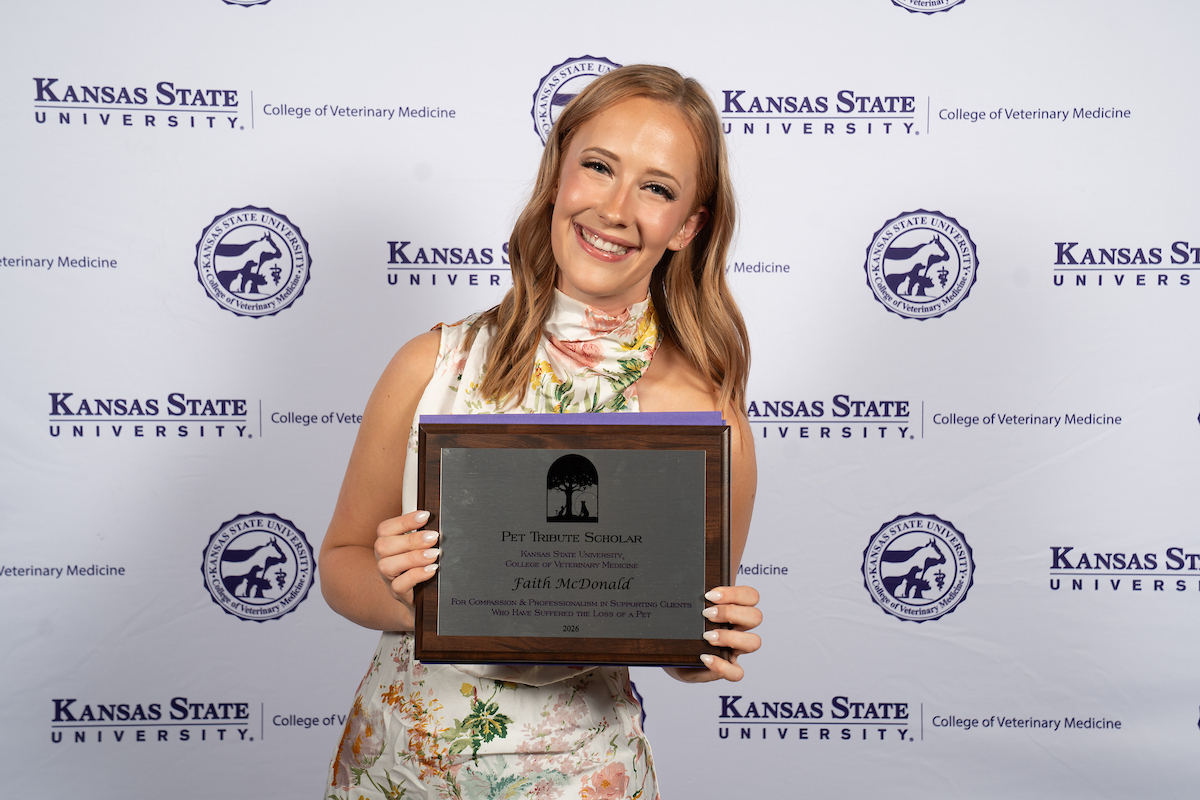 One person stands in front of a backdrop smiling.