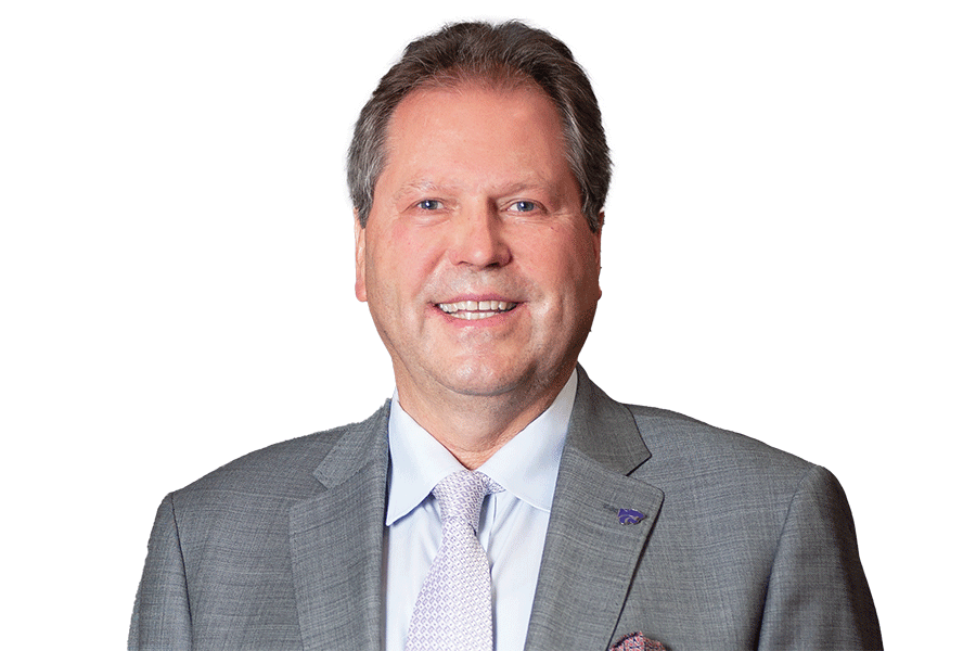 A man in a suit and tie smiles confidently, showcasing a professional appearance.