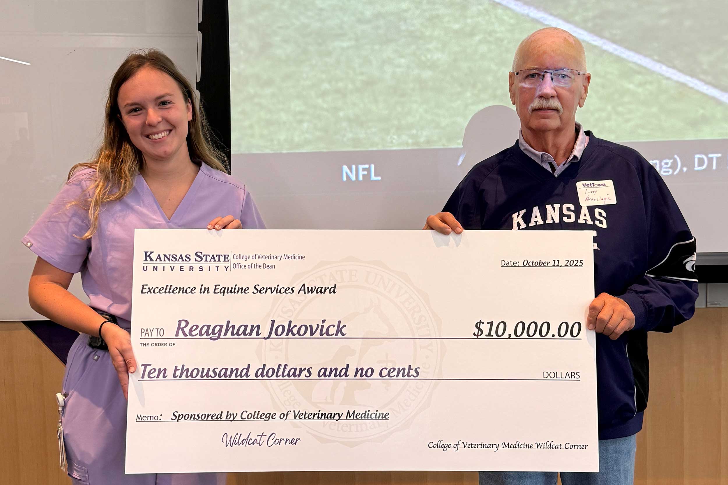 Alumnus poses with equine veterinary student and giant check