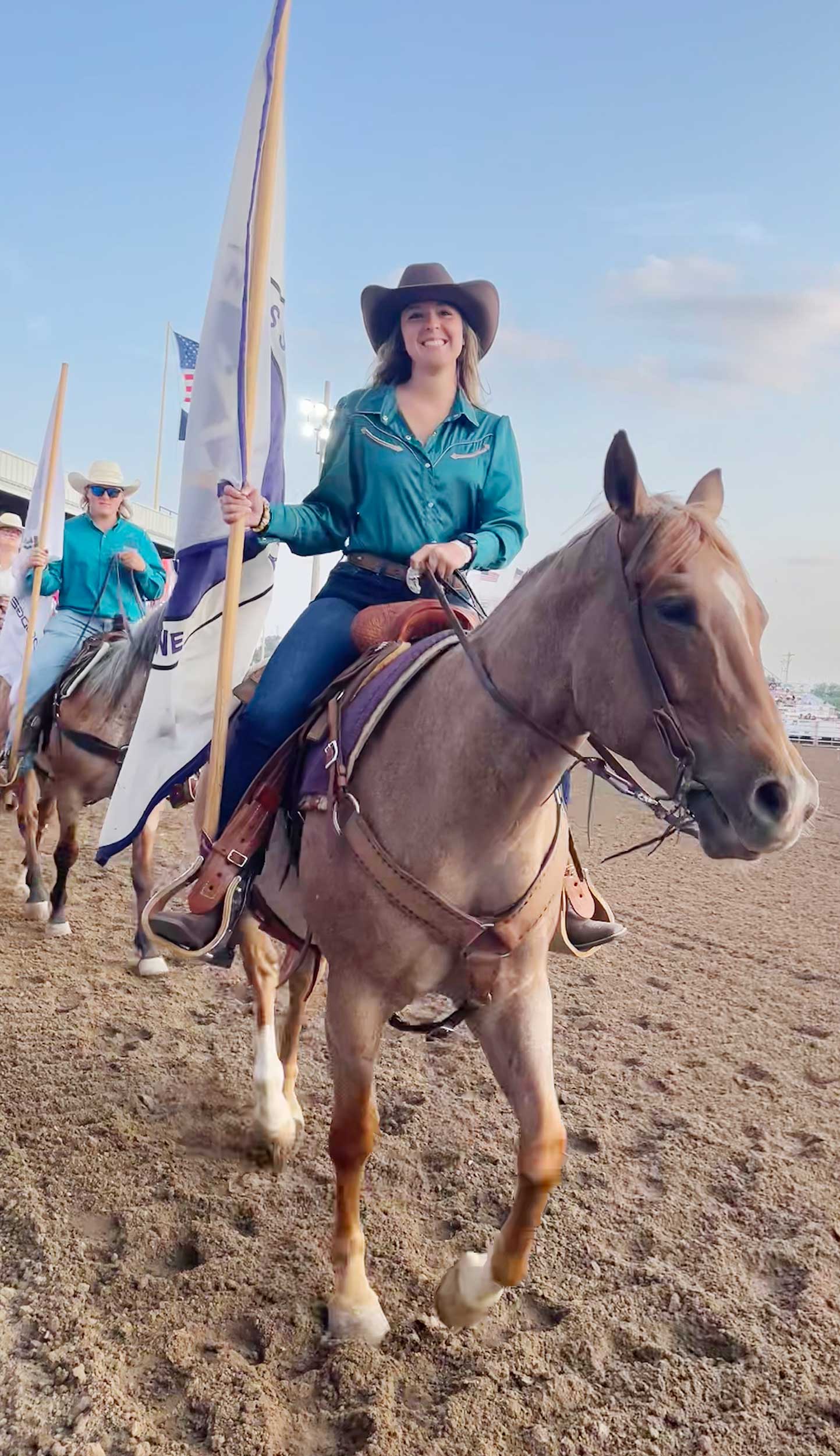 Girl rides horse at rodeo with flagg