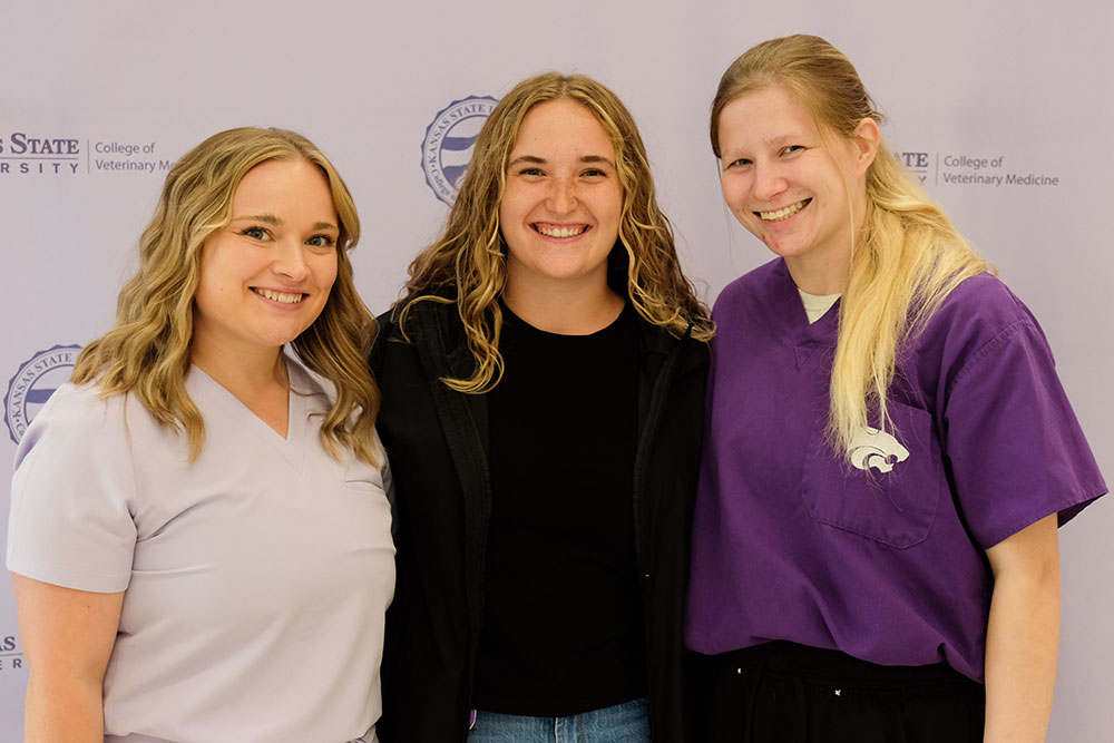 Ivy Elkins, Maeve Kumke and Elizabeth Scarbrough stand in front of a lavendar backdrop.