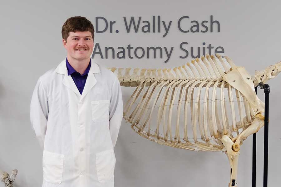 Dr. Konnor Stueve stands in front of Wally Cash Anatomy Lab sign