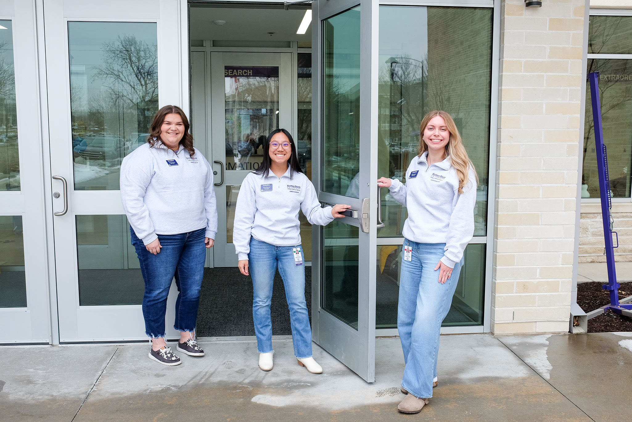  Three women holding the front doors of Trotter hall open.