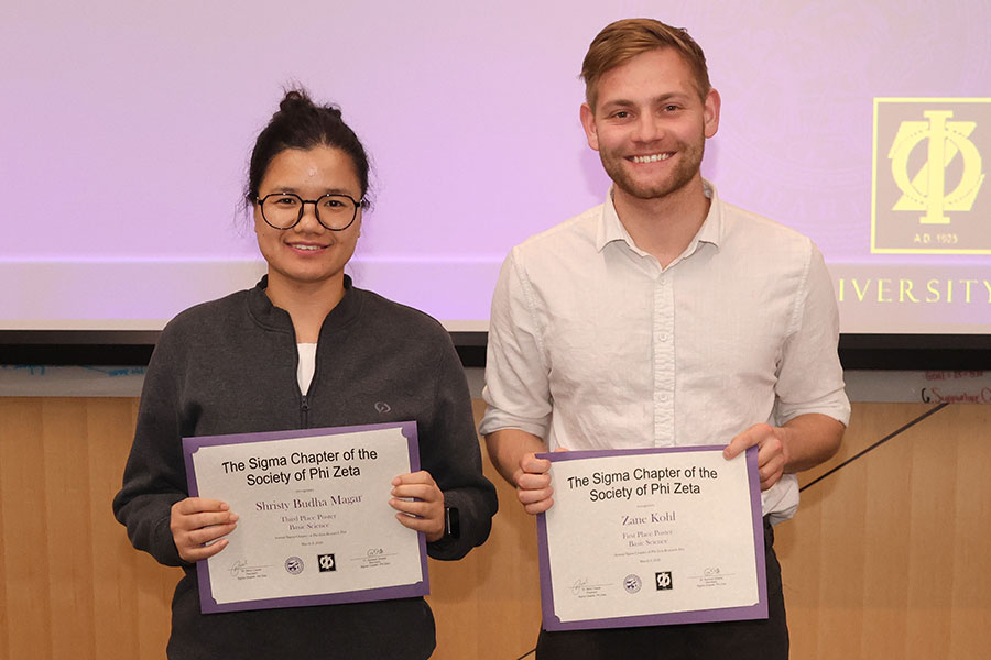 Two students hold certificates