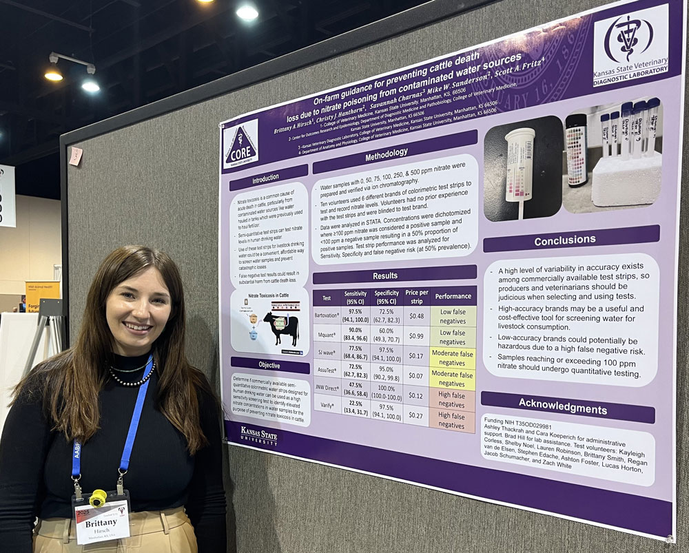 Student Britany Hirsch stands smiling next to her poster
