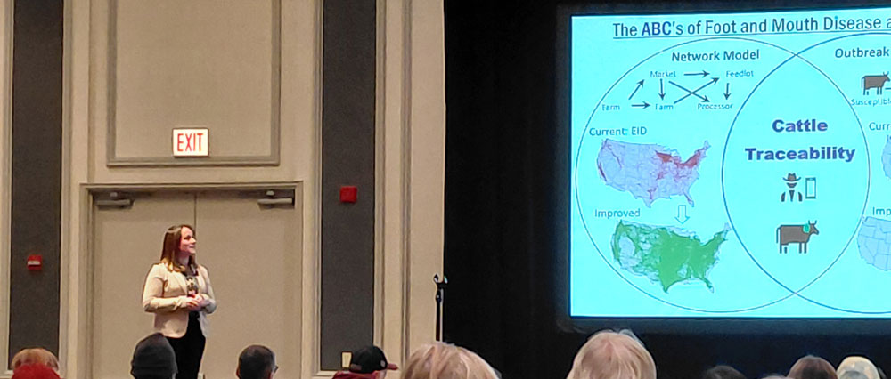 MaRyka standing on stage looking at the slide display next to her.