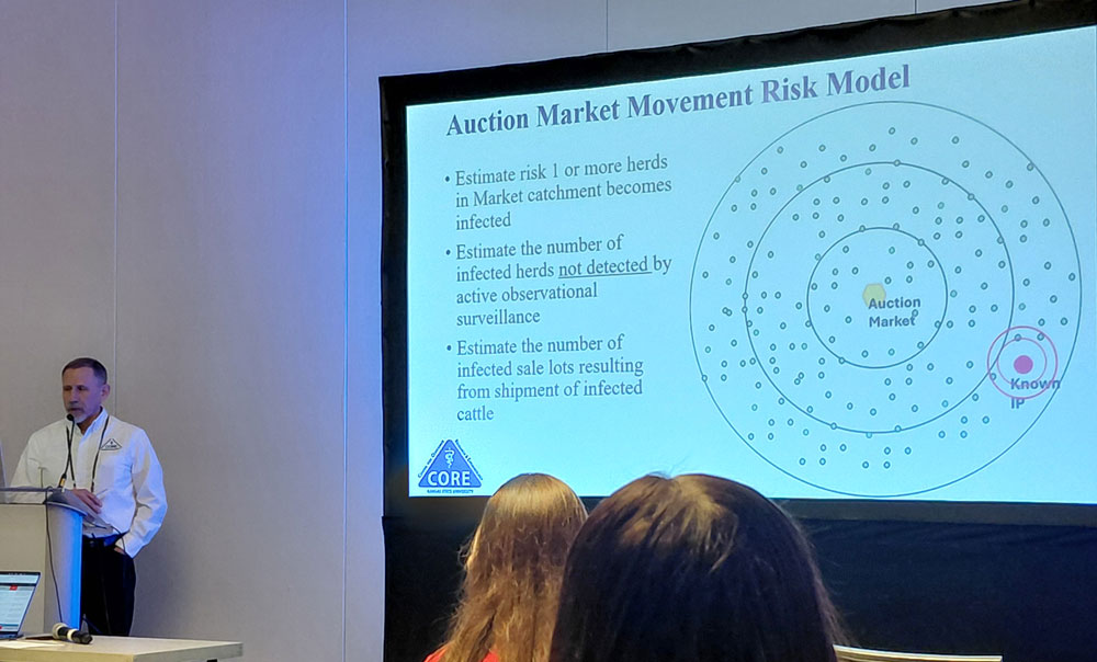 Dr Sanderson at a podium with a powerpoint slide on display next to him