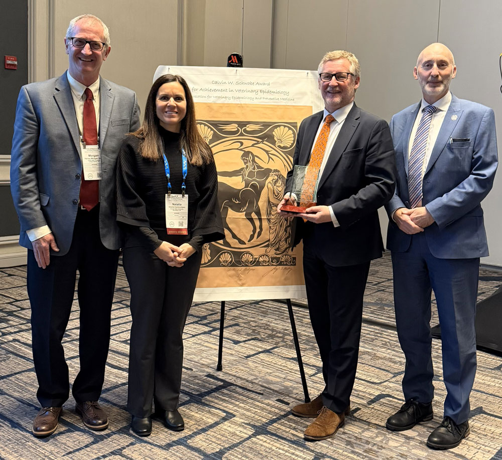 Three men and one woman standing in front of a poster display