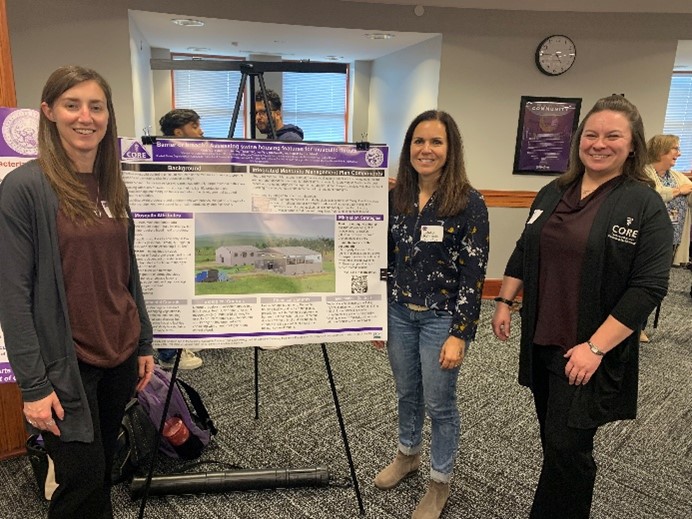 Three women standing next to a poster on an easel