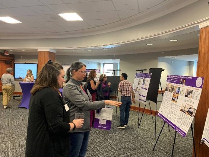 Two women looking at a poster, one is pointing at the poster
