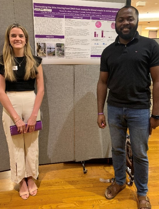 A woman and a man standing in front of a divider with a poster on it